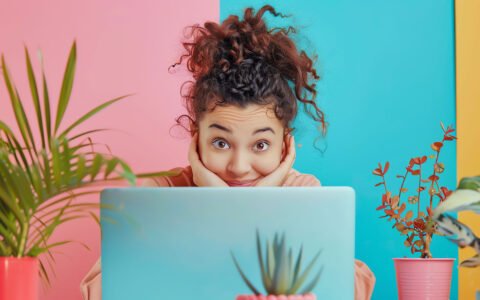 Woman peeking over a laptop, wondering how much a domain costs