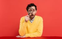 Man looking through a magnifying glass, representing SEO cost research